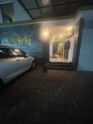 a car parked in a parking lot in front of a store at La Mer Inn in Kozhikode