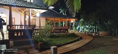 a building with benches in front of it at night at Wayal Wayanad Farm Resort in Panamaram