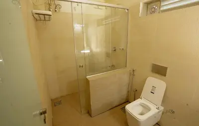 a bathroom with a toilet and a glass shower at IRON BRIDGE COVE in Meppādi