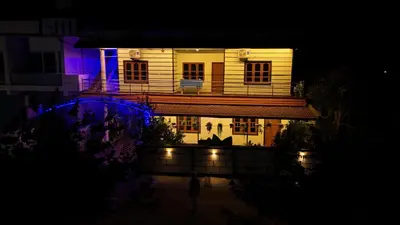 a house lit up at night with blue and purple lights at Coorg peacock feathers home stay in Kushālnagar