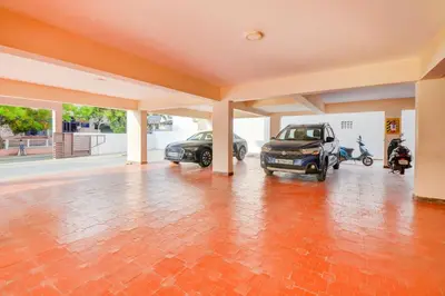 a large garage with two cars parked in it at Mayfair Service Apartments in Pīlamedu