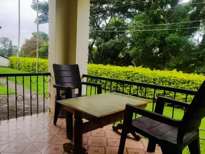 a porch with a wooden table and two chairs at Dubare Inn Coorg in Madikeri