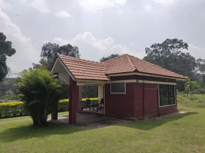 a small red brick house with a porch at Dubare Inn Coorg in Madikeri