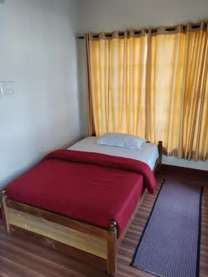 a small bedroom with a bed and a window at Dubare Inn Coorg in Madikeri
