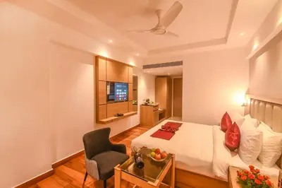 a hotel room with a bed and a chair at Emerald Clarks Inn Suites in Mysore