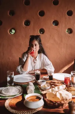a woman sitting at a table drinking from a glass at The Mudhouse Marayoor in Munnar