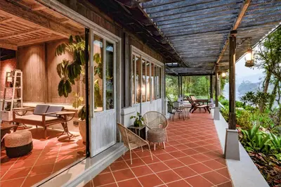 an outdoor patio with tables and chairs on a house at Periyar River Lodge in Thattakād