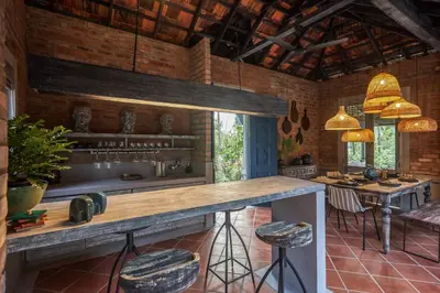 a kitchen with a counter and stools in a room at Periyar River Lodge in Thattakād