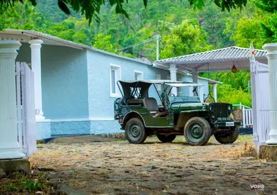 a green jeep parked in front of a house at Moonlight Munnar Forest Bungalow with Private Waterfalls by VOYE HOMES in Kanthalloor