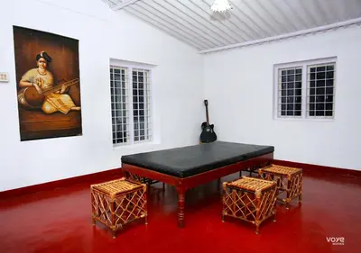 a black piano in a white room with two stools at Moonlight Munnar Forest Bungalow with Private Waterfalls by VOYE HOMES in Kanthalloor