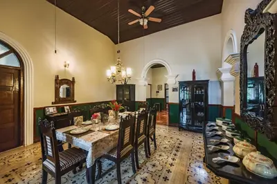 a dining room with a long table and chairs at SaffronStays Calamondinn Bungalow - 5BR Colonial Heritage Home within Coffee Plantation in Coorg in Gonikoppal
