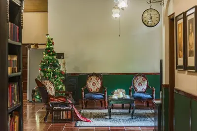 a living room with a christmas tree and chairs at SaffronStays Calamondinn Bungalow - 5BR Colonial Heritage Home within Coffee Plantation in Coorg in Gonikoppal