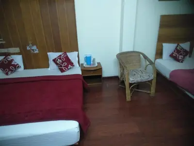 a room with two beds and a chair and a table at Red Star Holidays in Munnar
