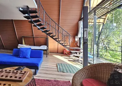 a living room with a blue couch and a staircase at Wild root stay- Orchid Chalet in Vythiri