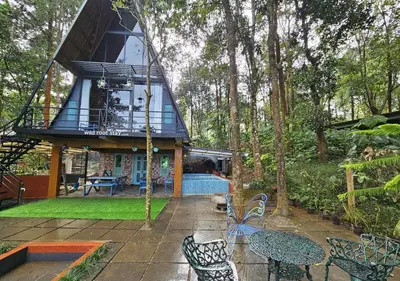 a house with a wrap around porch with tables and chairs at Wild root stay- Orchid Chalet in Vythiri