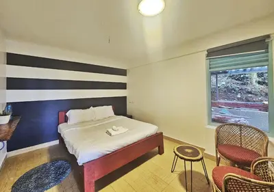 a bedroom with a bed and two chairs and a window at Wild root stay- Orchid Chalet in Vythiri