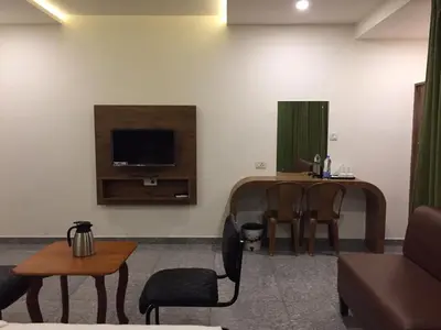 a living room with a tv and a table and chairs at Hillfort Inn in Sultan Bathery