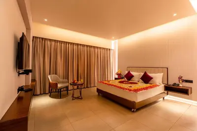 a bedroom with a bed and a table and a chair at Hotel M Pro Palace Mysore - 12 Minutes to Mysore Palace in Mysore