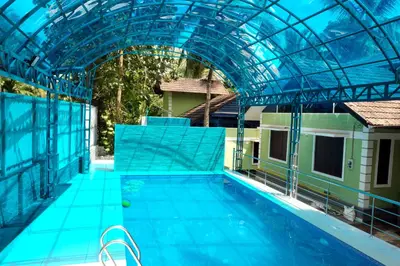 an indoor swimming pool with a glass roof and a swimming pool at NARMADA HOMESTAY Ganga in Perintalmanna