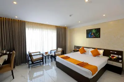 a hotel room with a bed and a table and chairs at Renai Sreekrishna in Guruvāyūr