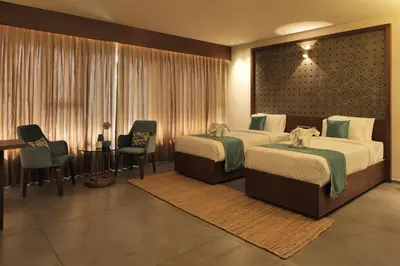 a hotel room with two beds and a table and chairs at GRANDE IRIS in Sultan Bathery