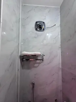 a bathroom with a shower with white marble walls at Sivamurugan residency in Bhavāni