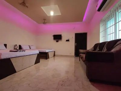 a room with two beds and a couch and a tv at Sivamurugan residency in Bhavāni