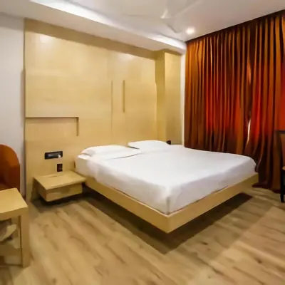 a bedroom with a large white bed and red curtains at PPH Living Railotel Coimbatore in Coimbatore