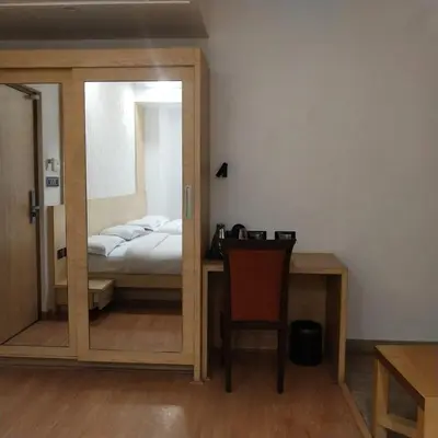 a mirror in a room with a bed and a chair at PPH Living Railotel Coimbatore in Coimbatore