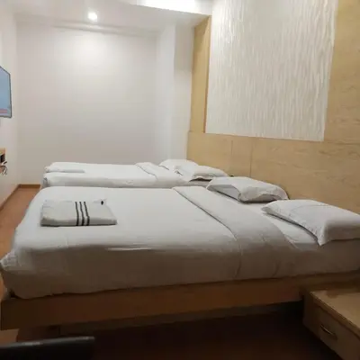 three beds are lined up in a room at PPH Living Railotel Coimbatore in Coimbatore