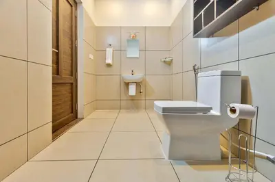 a white bathroom with a toilet and a sink at Serene Valley Resort Wayanad in Mananthavady