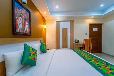 a bedroom with a large white bed with green pillows at Treebo Sree Varshavilas Regency, 500 Mtrs From Guruvayoor Temple in Guruvāyūr