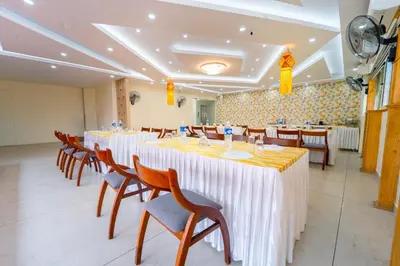 a banquet hall with tables and chairs with yellow and white table cloth at Treebo Sree Varshavilas Regency, 500 Mtrs From Guruvayoor Temple in Guruvāyūr