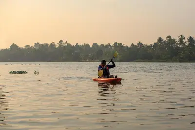 a man on a paddle board in the water at Lhasa Ayurveda and Wellness Resort - A BluSalzz Collection, Kochi, Kerala in Cochin