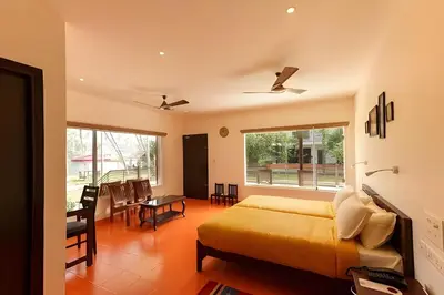 a bedroom with a bed and a dining room with a table at Lhasa Ayurveda and Wellness Resort - A BluSalzz Collection, Kochi, Kerala in Cochin
