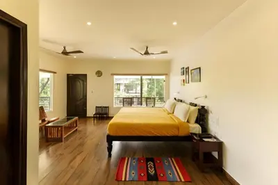 a bedroom with a bed with a yellow bedspread at Lhasa Ayurveda and Wellness Resort - A BluSalzz Collection, Kochi, Kerala in Cochin
