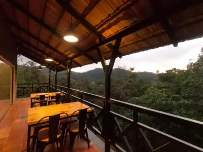 a porch with tables and chairs on a balcony at The Wild Trails Clarks Exotica , Munnar in Munnar