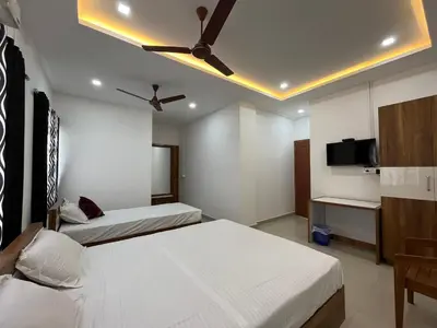 a bedroom with two beds and a ceiling fan at The Grand Inn in Kanjikode
