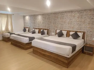 two beds in a bedroom with a brick wall at Hillcrest Metro in Ooty