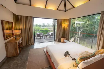 a bedroom with a large bed and a large window at Kaav Safari Lodge, Kabini in Begūr