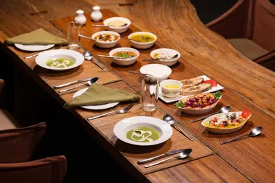a wooden table with plates and bowls of food at Kaav Safari Lodge, Kabini in Begūr