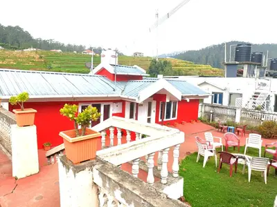 a red and white house with a table and chairs at QUEENS COTTAGE - individual cottage in Ooty