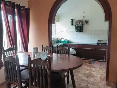 a dining room with a table and a kitchen at QUEENS COTTAGE - individual cottage in Ooty