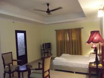 a bedroom with a bed and a table and chairs at Devasura inn in Guruvāyūr