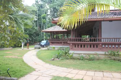 a red house with a car parked in front of it at Wayal Wayanad Heritage villa in Panamaram