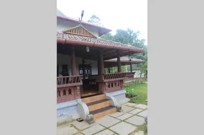 a building with a porch and stairs on it at Wayal Wayanad Honey moon villa in Panamaram