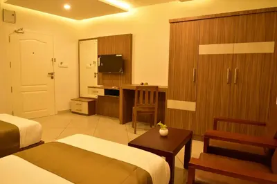 a hotel room with two beds and a television at WHITE SUITE HOTEL in Kozhikode