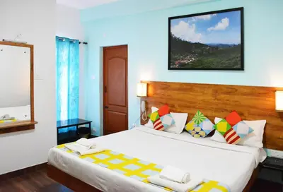 a bedroom with a large white bed and a mirror at EDEN Paradisee in Ooty