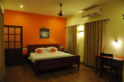 a bedroom with orange walls and a bed and a desk at The Villa Romantica in Nedumbassery