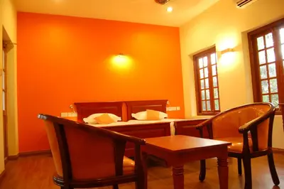 a dining room with orange walls and a table and chairs at The Villa Romantica in Nedumbassery